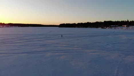 Hombre-Controlando-El-Dron-En-Medio-Del-Lago-Del-Río-Helado-Para-Ver-La-Puesta-De-Sol-En-Rovaniemi