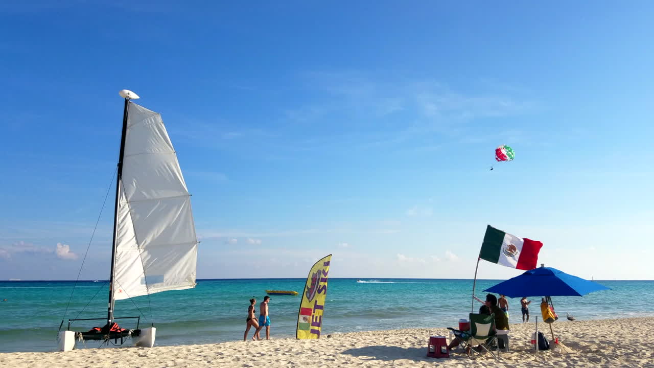 barco y deportes acuáticos en la playa con gente caminando en trajes de baño en playa del carmen méxico