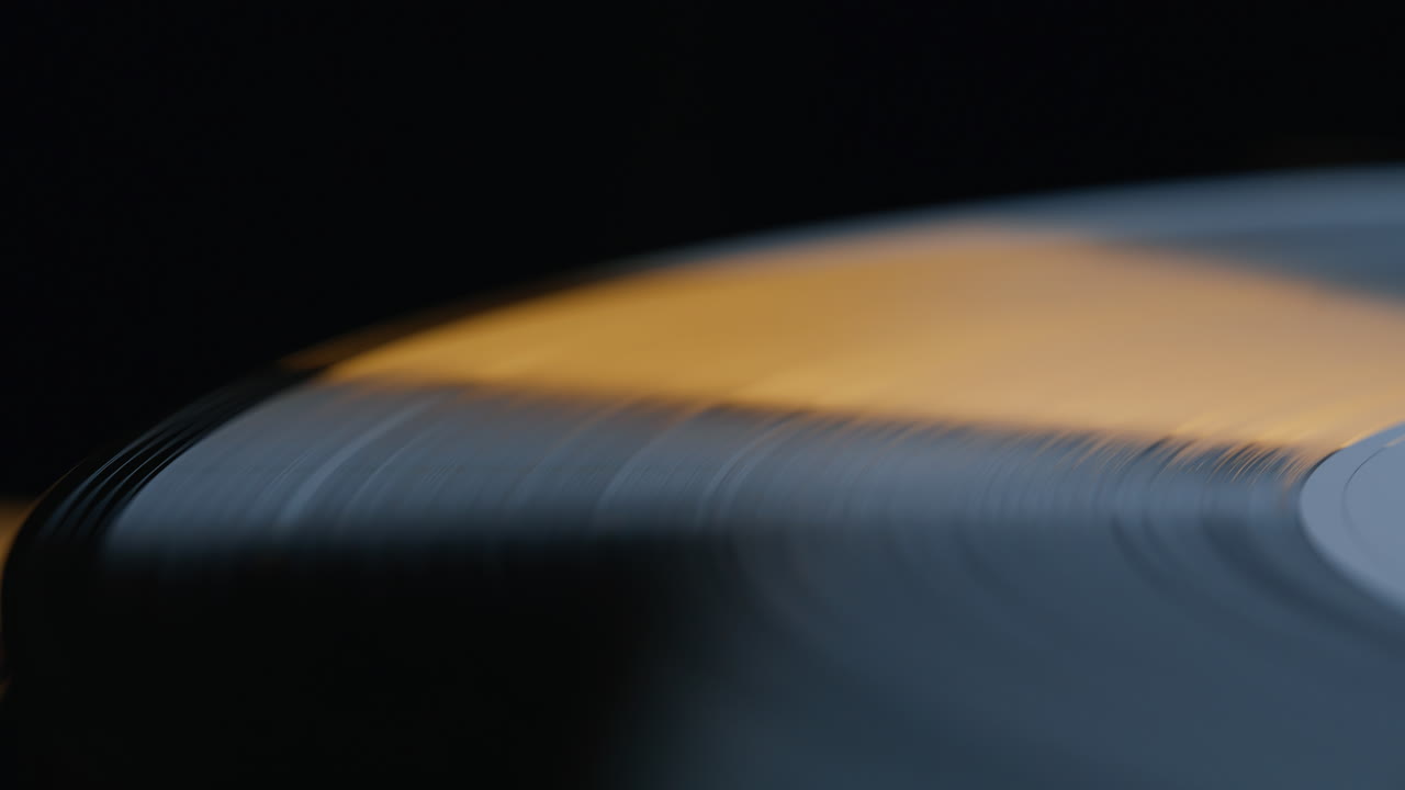 Closeup vinyl record rotating on black background. Macro view grooved disc