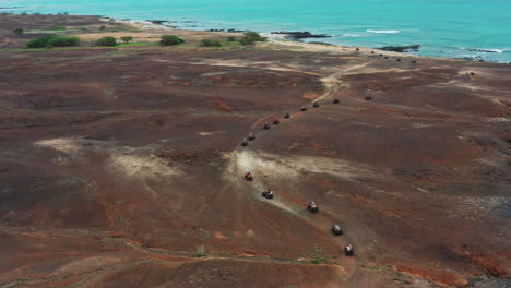 aerial shot of a quad bikes driving through the rough terrain, during an off road adventure,close to the coastline