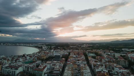 4k hyperlapse panning right to left over costa brava’s coastal town and bay, with dramatic sunset skies and distant mountains