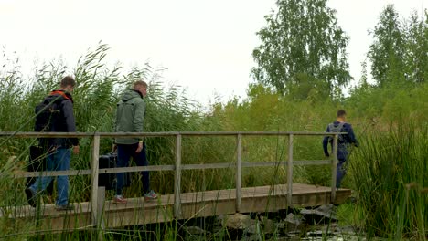 people walking across a wooden bridge in a marsh