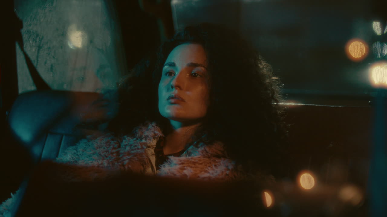 Young Thoughtful Woman Resting in Backseat of Car at Night