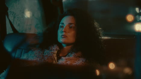 young thoughtful woman resting in backseat of car at night