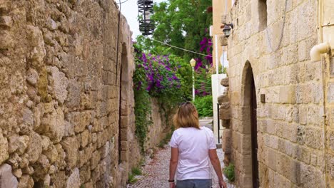 mujer turista caminando por un estrecho callejón vacío en cámara lenta en la vieja ciudad de europa