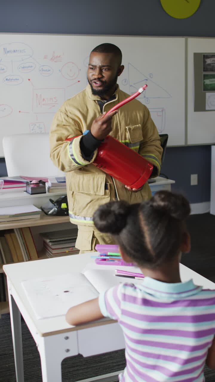Vertical video of happy african american male teacher with diverse schoolchildren learning