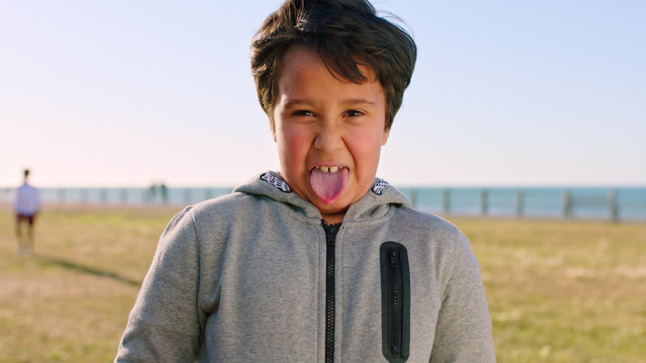 아이, 재미있는 얼굴과 혀를 꺼낸 해변 공원