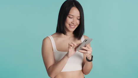 Mujer-Asiática-Enviando-Mensajes-De-Texto-En-Un-Teléfono-Inteligente-Y-Sonriendo.