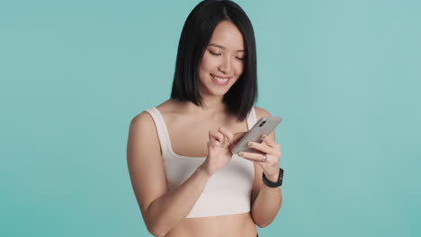 Asian-woman-texting-on-smartphone-and-smiling.