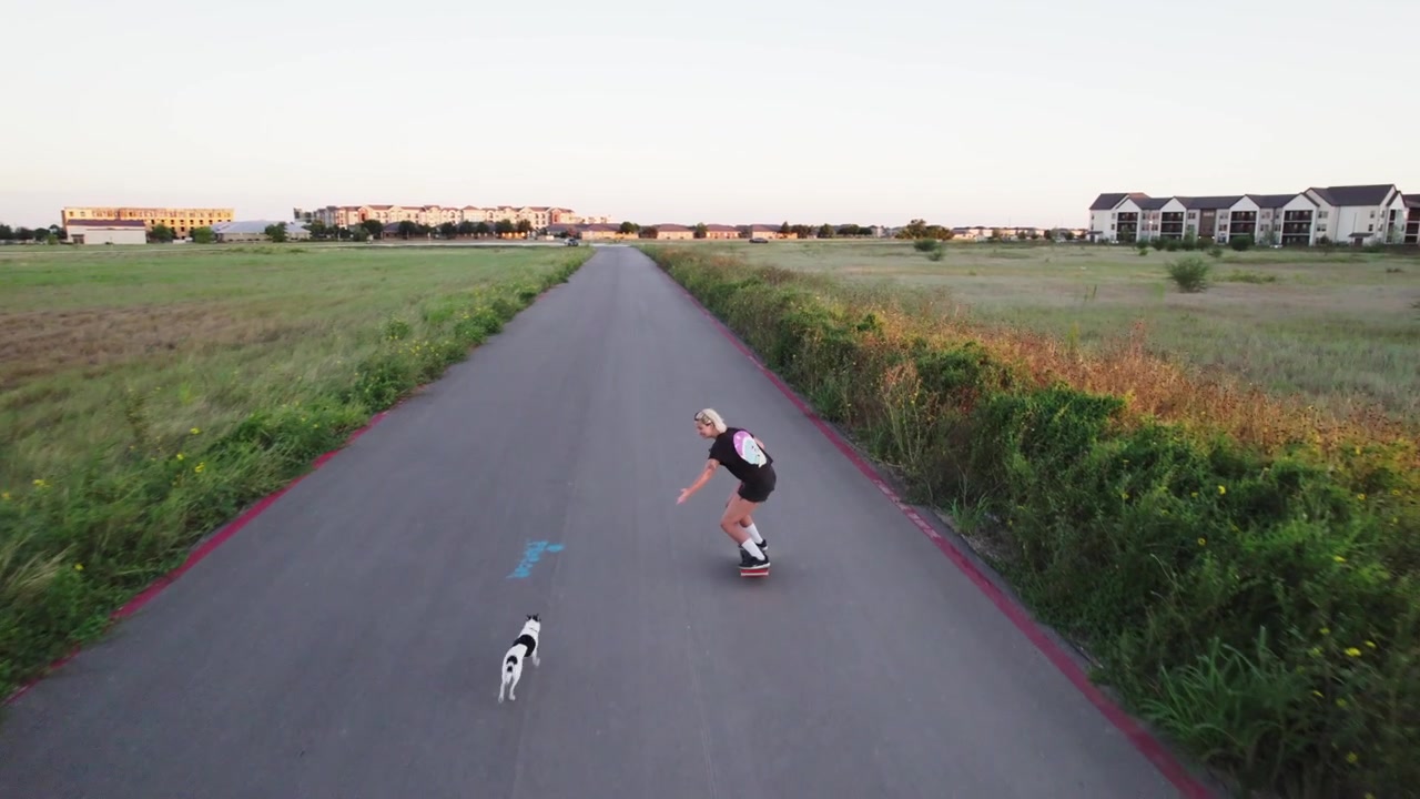 Vista aerea di qualcuno che guida senza sforzo un Onewheel, esplorando un vasto spazio aperto sottostante.