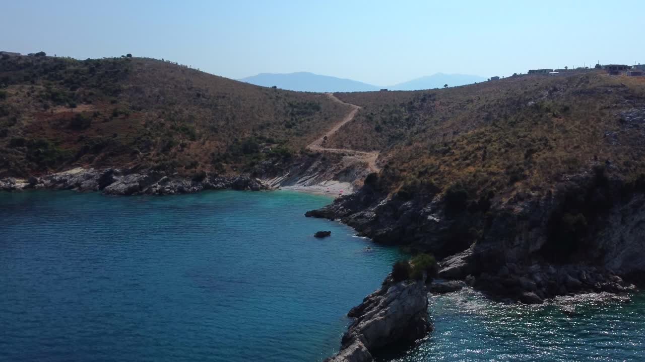 Drone shot of a lonely beach on the Mediterranean sea - drone is circling around the coast, facing the beach near Ksamil, Albania