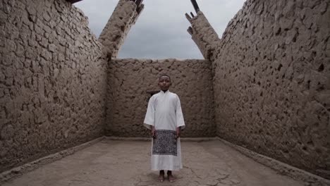 young boy wearing traditional religious clothing standing in the center of a mud church in ethiopia, representing spirituality, tradition, and cultural heritage