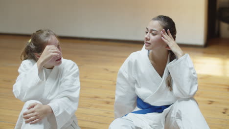 cámara lenta de chicas en kimonos hablando en el gimnasio después del entrenamiento