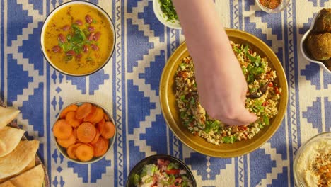 adding greenery in bulgur with eggplant close-up, bean soup, carrot, pita on table. traditional middle eastern culture. delicious rice with meat. arabian cuisine. homemade food concept