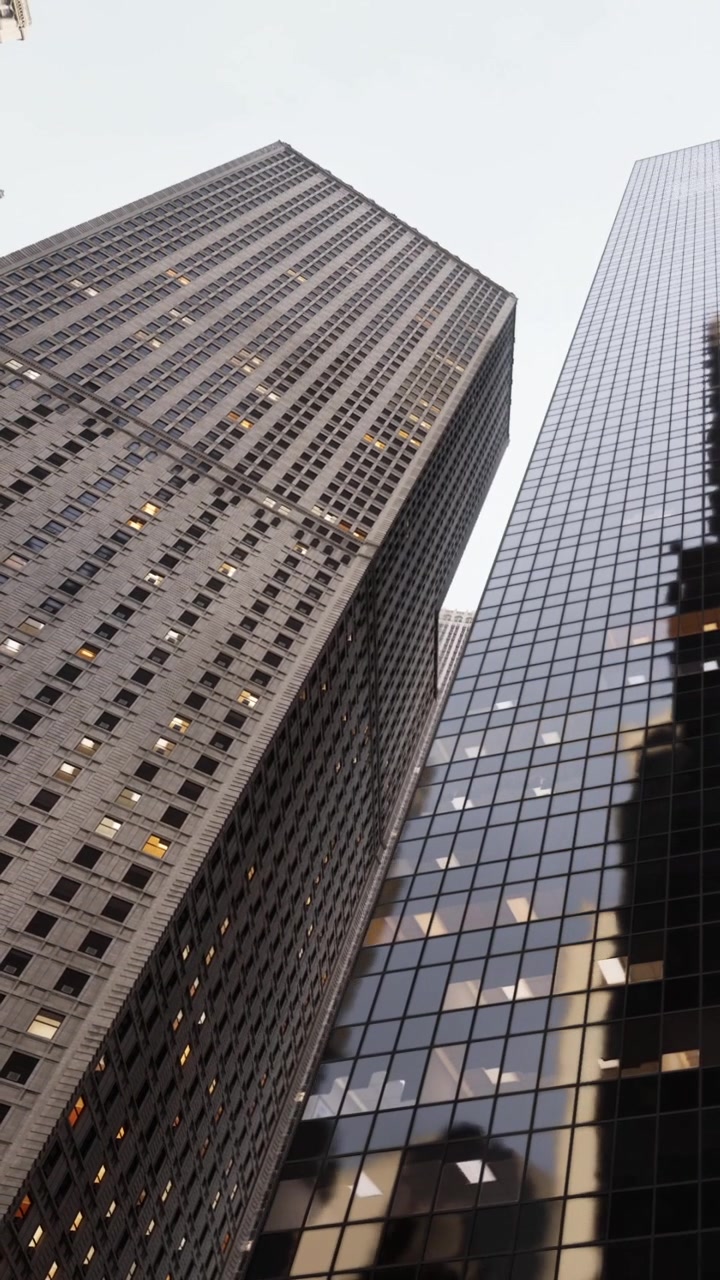 Edifici moderni svettano in una città con molte finestre sotto una luce intensa.
