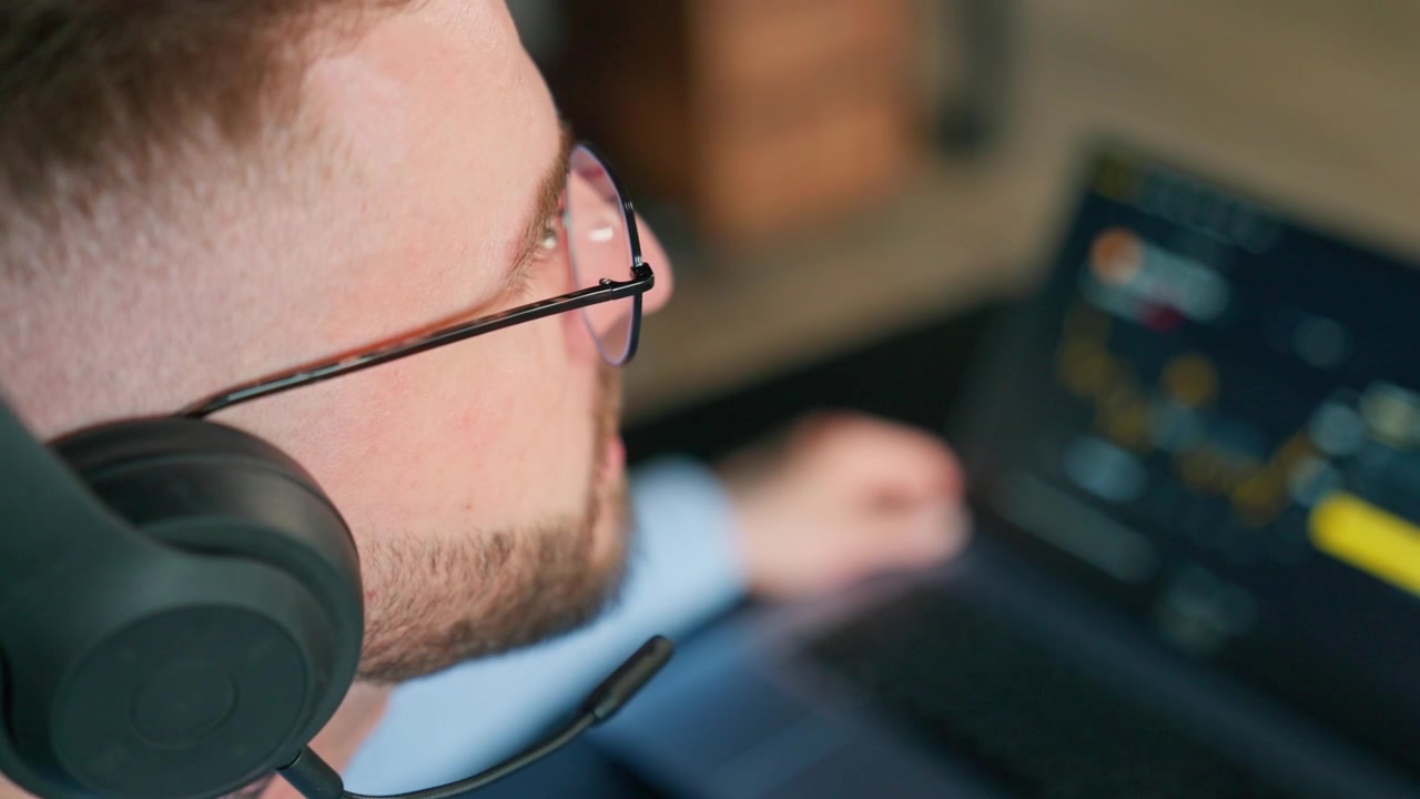 Man in Headphones Analyzing Financial Data on Laptop Screen