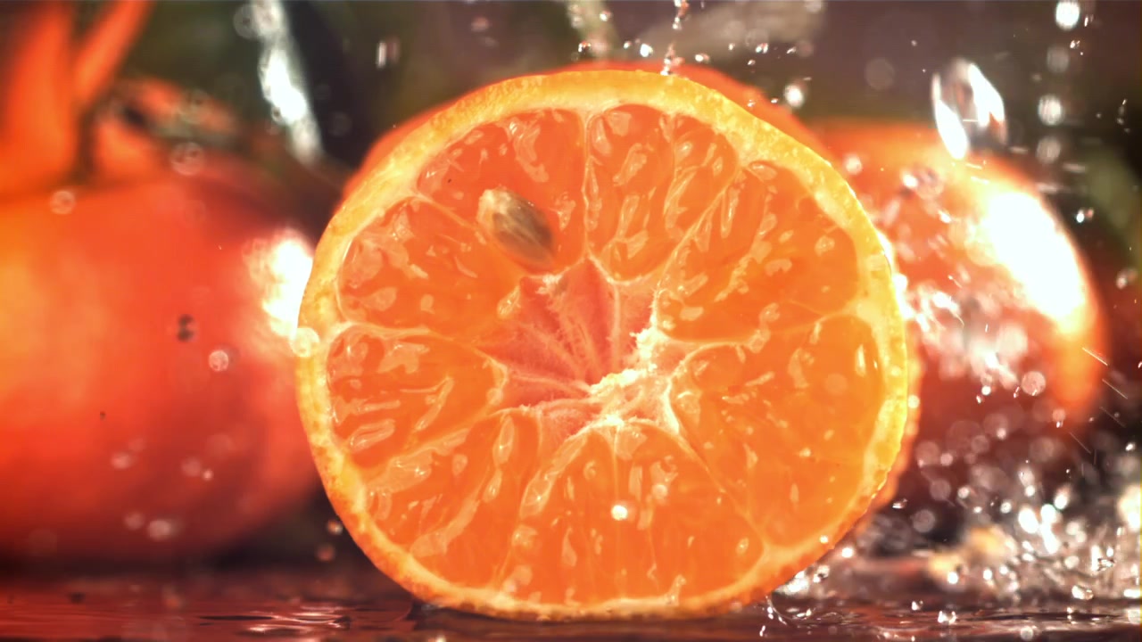 Frisk halveret appelsin med vandstænk i slow motion.
