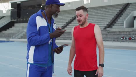 entrenador masculino afroamericano y atleta caucásico hablando durante una sesión de entrenamiento