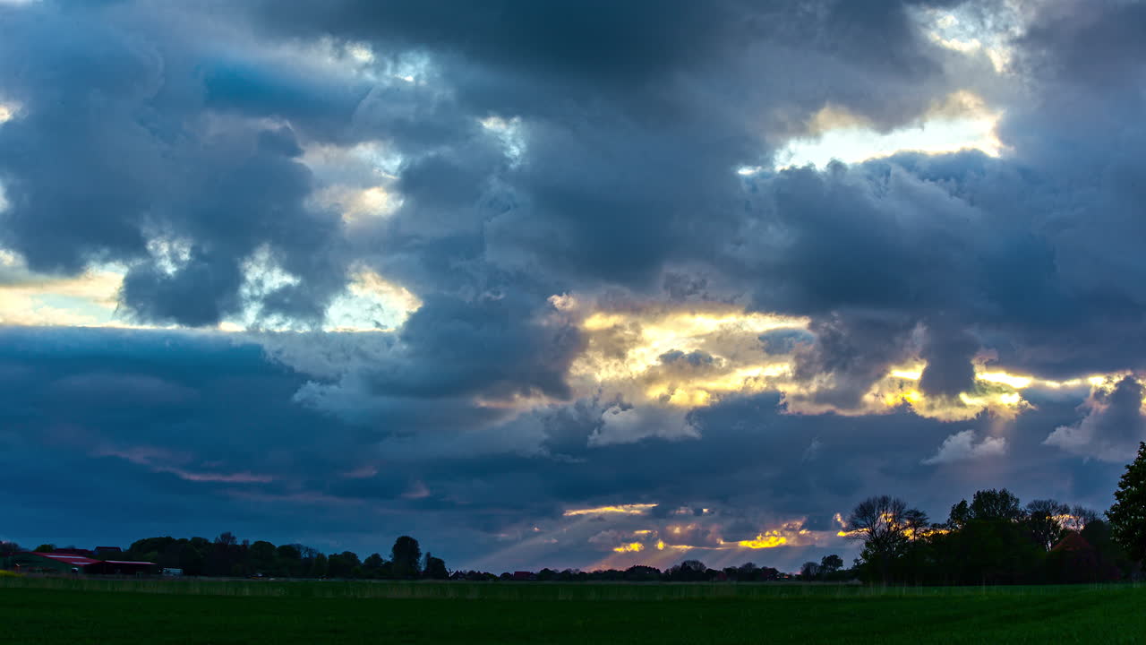 바람에 의해 운반되는 구름의 극적이고 빠른 움직임, 어두운 풍경 위에 주황색 빛으로 빛나는 태양 - 타임랩스 잠금 샷