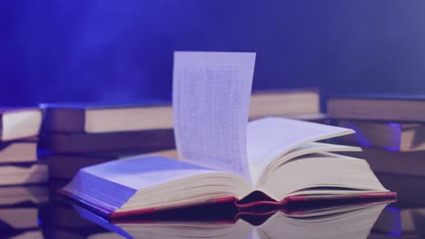 video of pages in book moving over books and smoke on black background