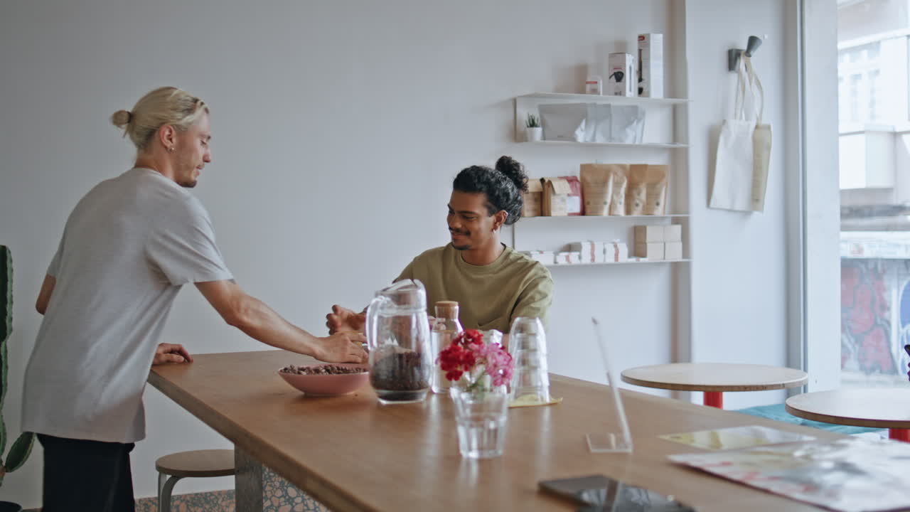 el camarero del café trae la taza de café al hombre latino sentado en la mesa.