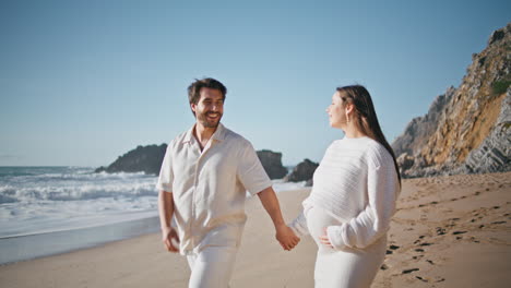 pareja embarazada caminando por la costa del océano disfrutando de la naturaleza soleada. pareja embarazada playa