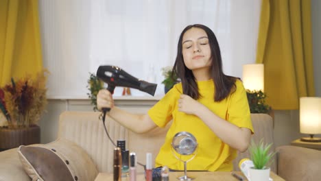 young woman blow drying her hair.