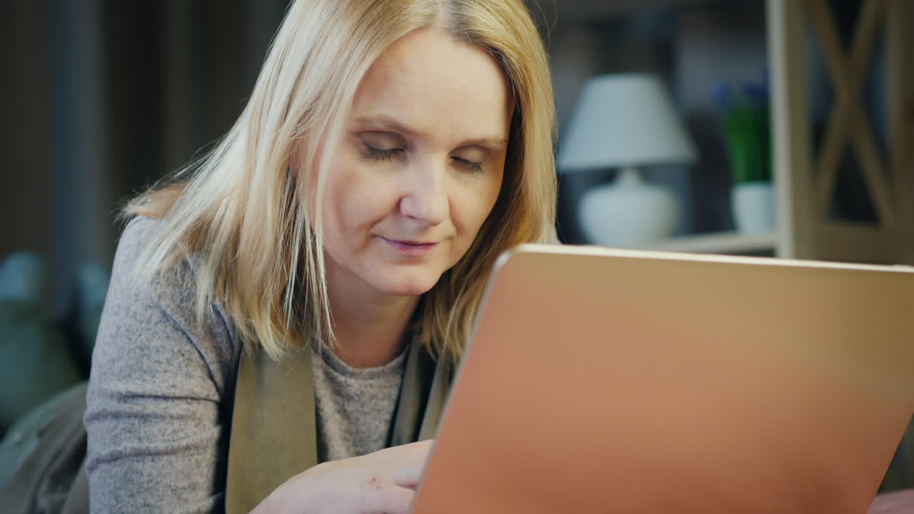 una mujer de mediana edad usa una computadora portátil en su cama 3