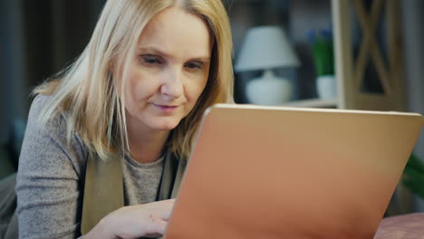 a middle-aged woman uses a laptop on her bed 3