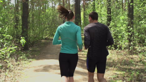 sporty couple running through the forest