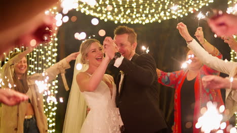 happy bride and groom dance with wedding guests lit by sparklers and lights, 4k slow motion