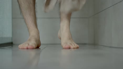 man dries his legs after showering