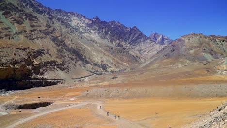 hikers passing through a desert-like valley in the mountains on a bright sunny day