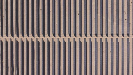 granja solar en un desierto iluminado por el sol durante el día, aérea de arriba hacia abajo