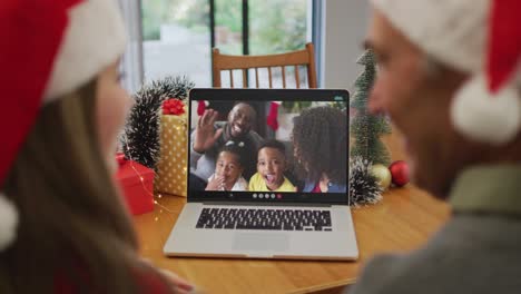 Caucasian-grandfather-and-grandaughter-on-video-call-on-laptop-with-family-at-christmas