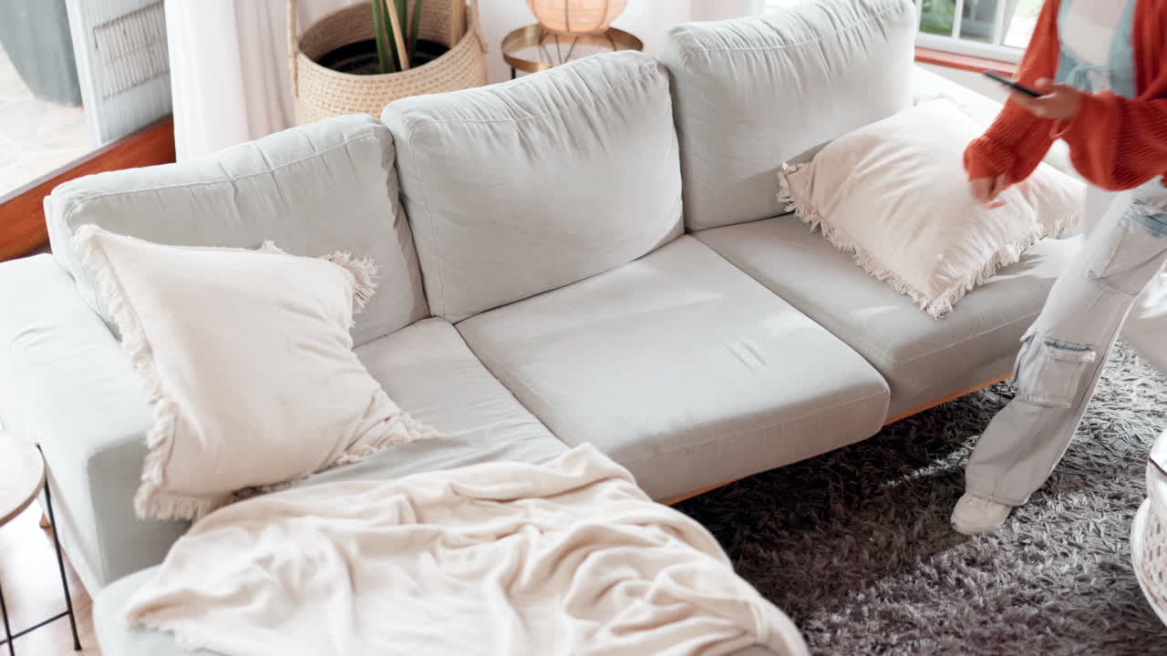 mujer joven relajándose en un sofá, usando un teléfono móvil