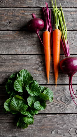fresh beets, carrots, and greens on a wooden table