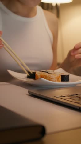 woman eating sushi at her laptop