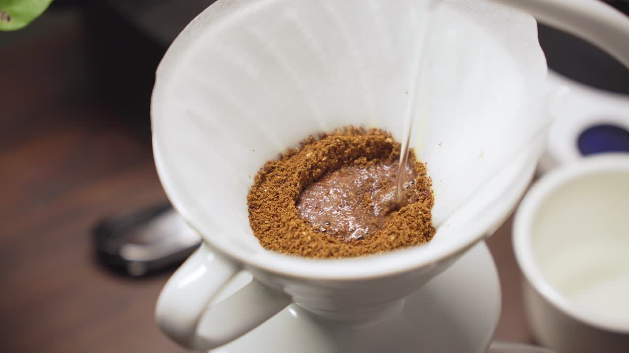 바리스타는 은 커피 콩 위에 거위 목을 가진 비에서 뜨거운 물을 부어