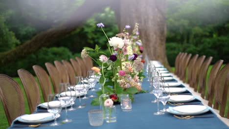 exquisite spring wedding reception setup with fresh flowers on a long blue table in the garden