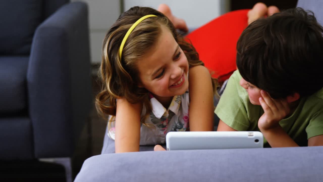 hermanos usando tableta digital en la sala de estar