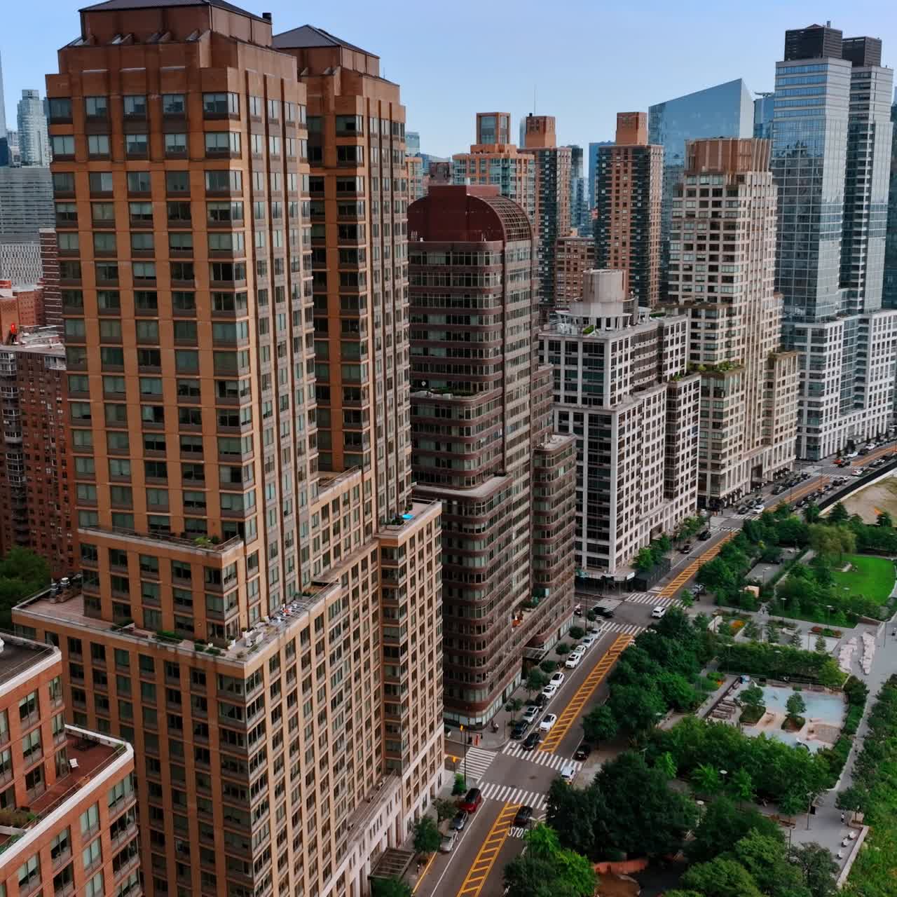 Closer look on the beautiful New York buildings standing near the waters of Hudson. Cozy green areas and lively highway near the buildings. Top view