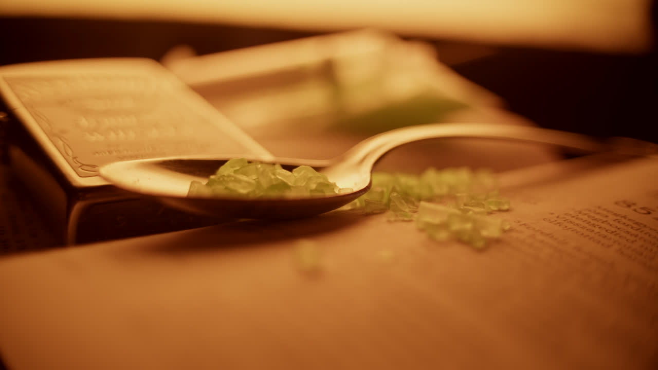 Green Crystals on a Spoon Resting on an Old Book