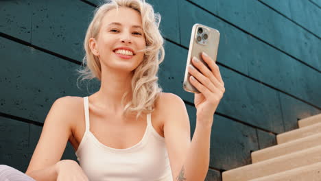 woman smiling at phone on steps