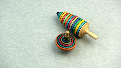 two wooden colorful top spin whirligig on table background