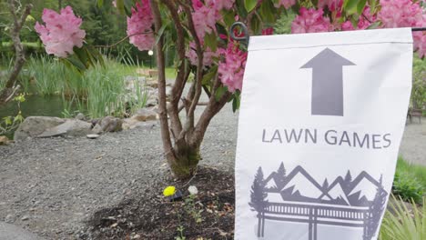 lawn games sign in a farm with a pink azalea tree