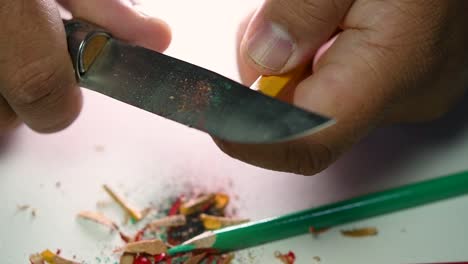 Footage-of-hands-slowly-sharpening-a-pencil-and-some-coloured-pencils-with-a-sharp-knife