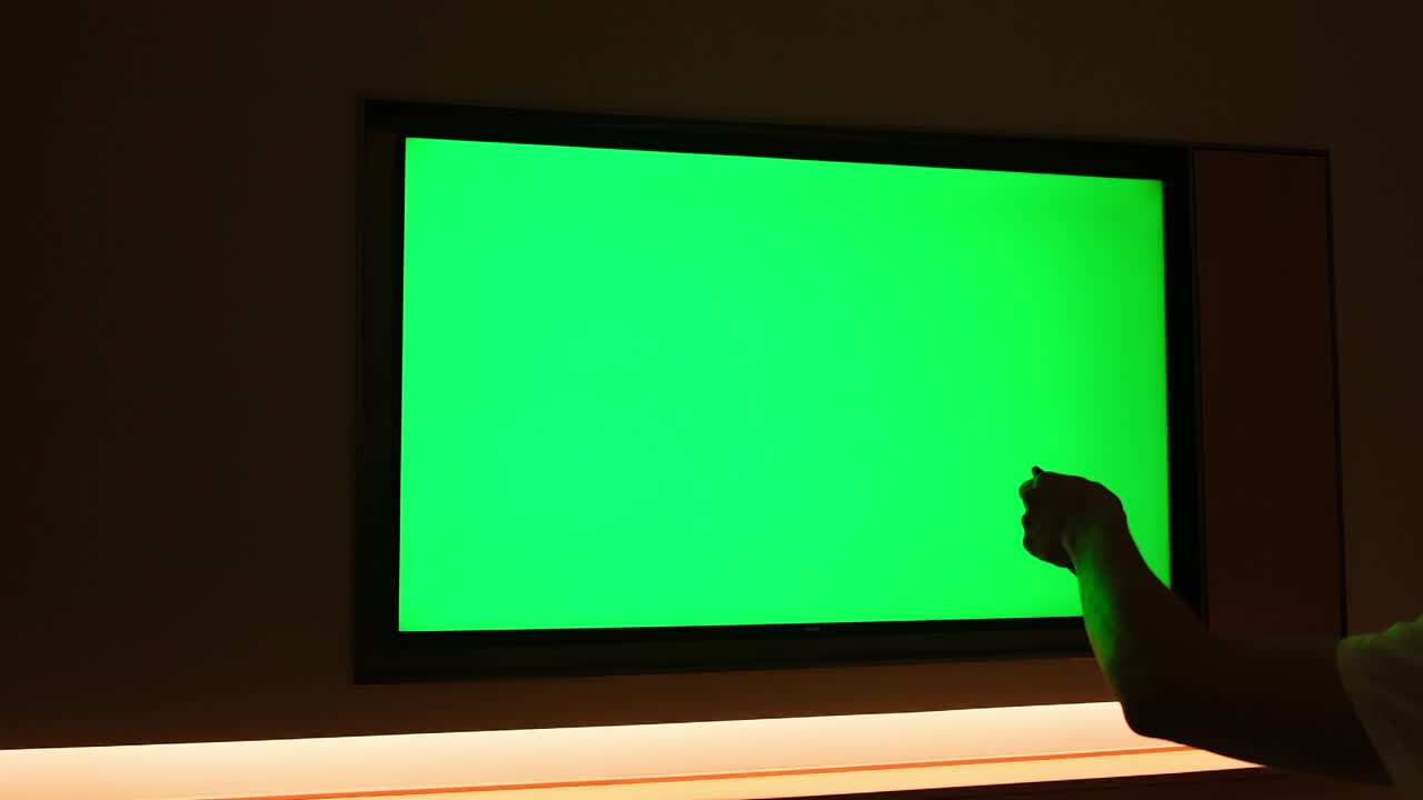 people watching large green screen TV at dark night