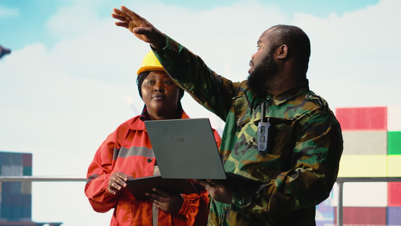 Military personnel on offshore rig analyzing tactical data on laptop
