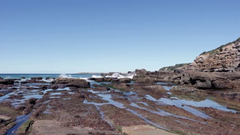 Cueva-De-La-Playa-En-La-Bahía-De-Jervis,-Australia,-área-De-La-Piscina-De-Mareas-Bañada-Por-Las-Olas-Del-Océano,-Tiro-De-ángulo-Bajo-Bloqueado